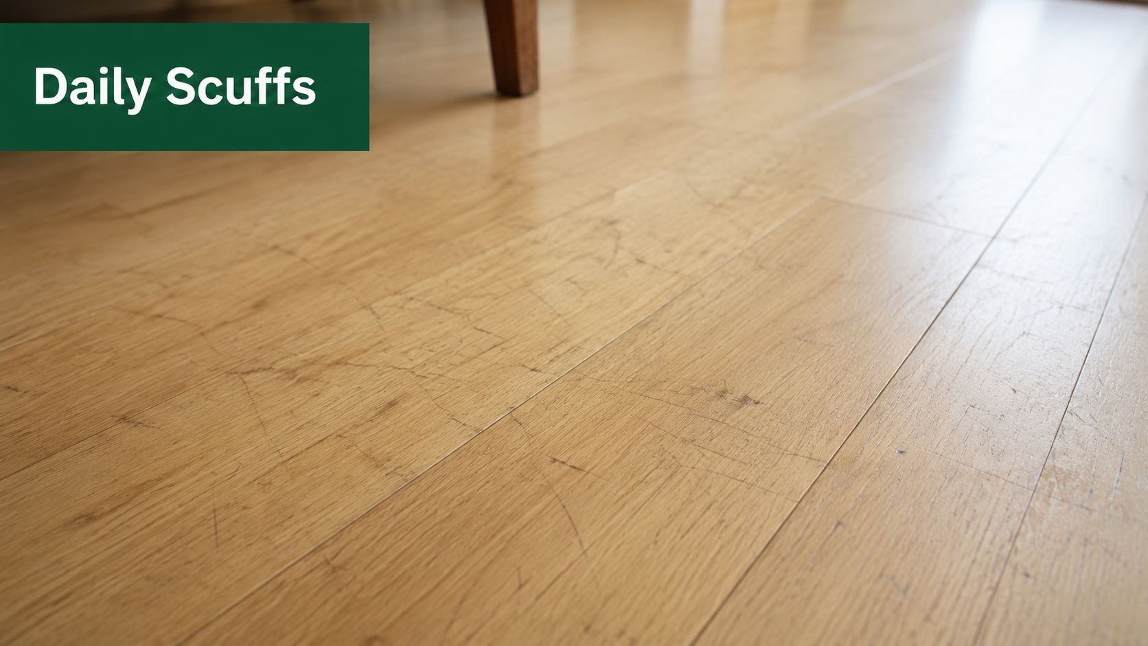 A close-up view of a light oak wooden floor showing various surface scuffs and minor scratches.